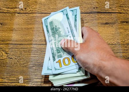 Der Mann am Tisch hält Rechnungen. Dollar in der Hand. Stockfoto