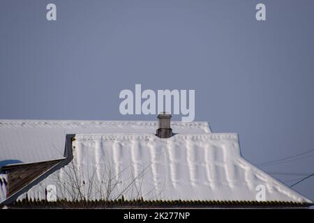 Das Dach des Hauses liegt im Schnee. Haus mit Kamin. Stockfoto