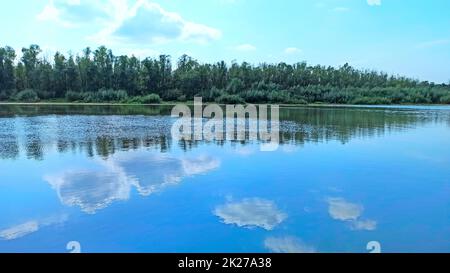 Landschaft mit Fluss im Frühling. Bäume spiegeln sich im Wasser des Flusses wider Stockfoto