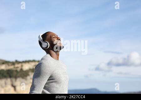 Glücklicher Mann atmet und hört draußen Musik Stockfoto