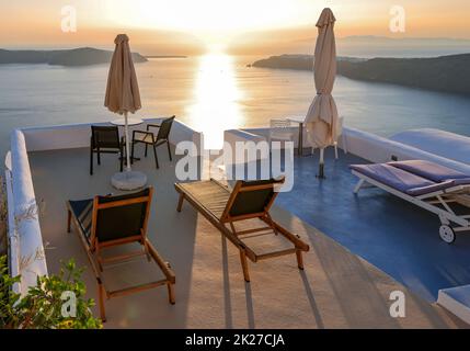 Sonnenliegen auf der Terrasse im Dorf Imerovigli mit herrlichem Blick auf den Sonnenuntergang über der Caldera in Santorin Stockfoto