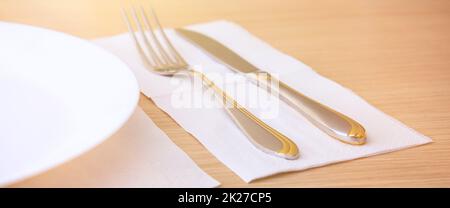 Eine leere Platte, Gabel, Messer, auf einem Holztisch, Seitenansicht. Stockfoto