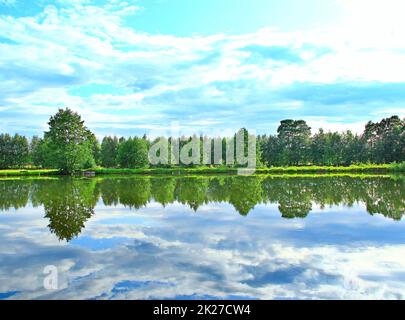 Landschaft mit Fluss im Sommer. Bäume spiegeln sich im Wasser des Flusses wider Stockfoto