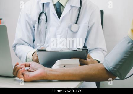 Der Arzt misst den Blutdruck eines älteren männlichen Patienten. Stockfoto