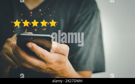 Hand mit Telefon halten 5 Sterne auf Händen.Kundenzufriedenheit und Marketing-Umfrage Bewertungskonzept Stockfoto