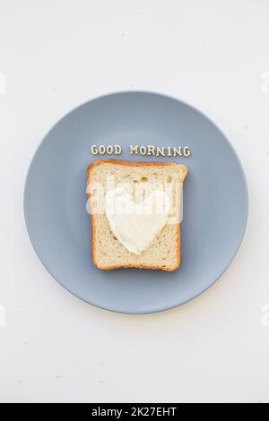 Sandwich zum Frühstück in Herzform mit Käse auf einem blauen Teller. Guten Morgen Stockfoto