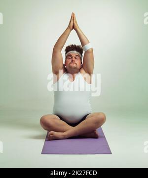 Fit zu sein ist besonders beim Yoga einfach. Ein übergewichtiger Mann, der eine Yoga-Pose macht. Stockfoto
