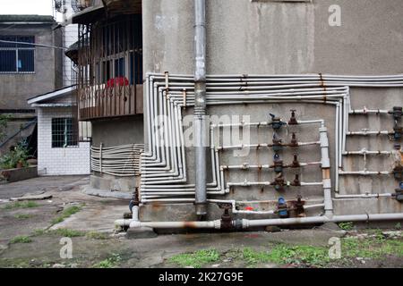 Rohre und Meter einer Nachbarschaft, die sich außerhalb in einer Wohnumgebung mit schlechter Infrastruktur gegenüberstellt Stockfoto