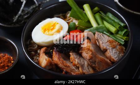 Ramen-Suppe mit hartgekochtem Ei, Gemüse, Schweinefleisch, Sojasauce. Japanischer Tonkotsu Ramen, Schweineknochenbrühe Nudeln Stockfoto