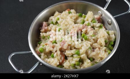 Klassisches italienisches Risotto mit Erbsen, Käseparmesan, Prosciutto. Risi e Bisi (venezianischer Reis und Erbsen) Stockfoto