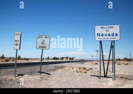 Das Schild "Welcome to Nevada" mit anderen Hinweisen mitten in der Wüste Stockfoto