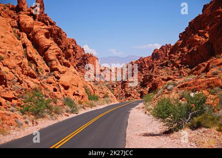 Die Asphaltstraße in der Mitte des Tals, umgeben von roten Felsen Stockfoto