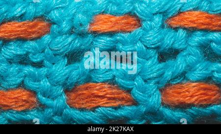 Blaues Wollgewebe mit orangefarbenen Fäden. Gestrickter Hintergrund Stockfoto