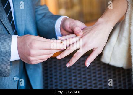 Der Bräutigam trägt einen Ring am Finger seiner Geliebten Stockfoto