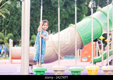 Ein Kind spielt auf dem Spielplatz im Freien, ein glückliches Kind im Vorschulalter, das Spaß hat, während es auf dem Spielplatz spielt Stockfoto