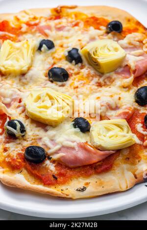 Pizza mit Schinken, schwarzen Oliven und Artischocken Stockfoto