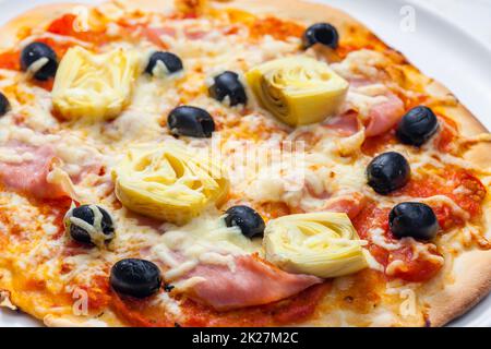 Pizza mit Schinken, schwarzen Oliven und Artischocken Stockfoto