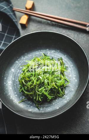 Grünes Wachspiel. Algensalat in Schüssel auf schwarzem Tisch. Stockfoto
