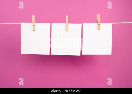 Leere weiße Blätter in einer Reihe, die an einer Schnur hängen, Platz für Bilder und Text, Nachrichtenkommunikation und Marketinghintergrund Stockfoto