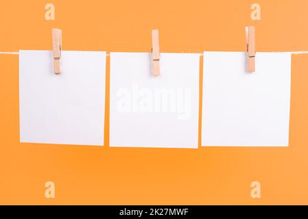 Leere weiße Blätter in einer Reihe, die an einer Schnur hängen, Platz für Bilder und Text, Nachrichtenkommunikation und Marketinghintergrund Stockfoto