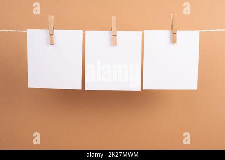 Leere weiße Blätter in einer Reihe, die an einer Schnur hängen, Platz für Bilder und Text, Nachrichtenkommunikation und Marketinghintergrund Stockfoto