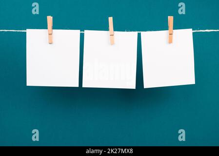 Leere weiße Blätter in einer Reihe, die an einer Schnur hängen, Platz für Bilder und Text, Nachrichtenkommunikation und Marketinghintergrund Stockfoto