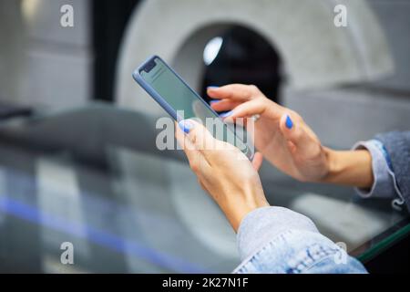 Das Mädchen sitzt in einem Café und hält ein Touch-Phone, einen Roboter und Kommunikation über das Internet. Online-Roboter, Fernzugriff. Stockfoto