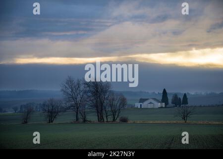 Abendlandschaft - Himmel mit Wolken über Wiesen und Wald. Stockfoto