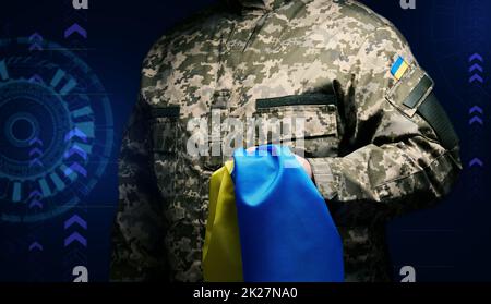 Soldat der ukrainischen Streitkräfte steht mit einer blau-gelben Flagge der Ukraine auf schwarzem Hintergrund. Wir ehren Veteranen und gedenken denen, die im Krieg getötet wurden Stockfoto