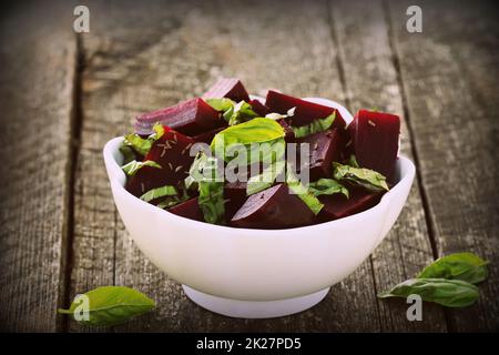 Rote Bete für Salat mit Basilikum und Dill Samen in der Schüssel gehackt auf rustikalen Holztisch Stockfoto