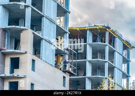 Baustelle mit Kran. Langfristiger Bau. Ein neues Gebäude im Bau, von unten nach oben. Unfertiger Wolkenkratzer, gefrorener Bau. Unfertiger Bau einer mehrstöckigen Wohngegend Stockfoto