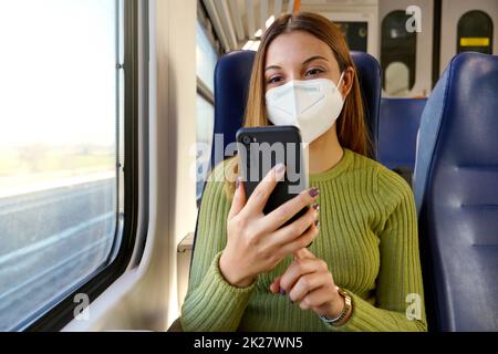 Trainieren Sie den Passagier mit der Smartphone-App während der Fahrt zur Arbeit und tragen Sie eine Gesichtsmaske Stockfoto