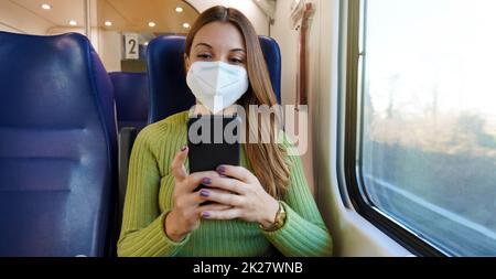 Entspannter Zugpassagier mit Smartphone-App während der Fahrt auf dem Weg zur Arbeit mit Gesichtsschutzmaske. Panorama-Banner über den Lebensstil von Menschen beim Pendeln nach der Arbeit. Stockfoto