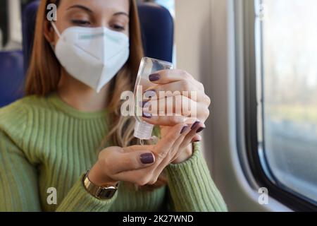 Geschäftsfrau mit medizinischer Gesichtsmaske mit Alkohol-Gel-Desinfektionsmittel Hände an öffentlichen Verkehrsmitteln. Antiseptikum, Hygiene und Gesundheitskonzept. Fokus auf die Hand mit der Alkohol-Gel-Flasche. Stockfoto