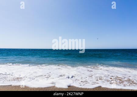 Blick von einem Strand mit Horizont über das Wasser an einem sonnigen Tag Stockfoto