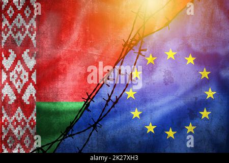 Grunge-Flaggen von Belarus und der Europäischen Union geteilt durch Stacheldraht mit Sonnentrübungen Stockfoto