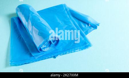 Eine Rolle Plastik-Müllsäcke in Blau auf blauem Hintergrund. Beutel, die für Müll ausgelegt sind, zu Hause verwendet und in verschiedene Müllcontainer gelegt werden. Stockfoto