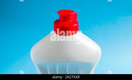 Weiße Kunststoffflasche mit Geschirrspülmittel, Bleichmittel oder Weichspüler auf blauem Hintergrund. Flüssiges Waschpulver. Der Begriff der Reinigung. Stockfoto