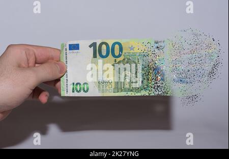 der in einer Hand gehaltene euro-Schein zerfällt und löst sich aufgrund der Inflation auf Stockfoto