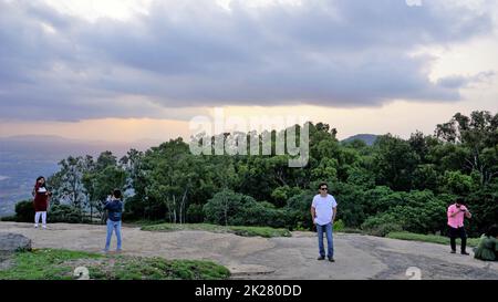 Nandi Hills, Karnataka, Indien-Mai 22 2022: Touristen genießen den wunderschönen Sonnenuntergang von der Spitze der Nandi Betta oder Nandidurg. Top Picknickplatz und Woche Stockfoto