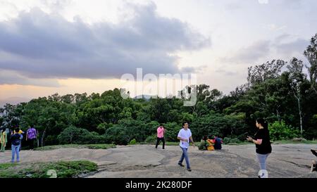 Nandi Hills, Karnataka, Indien-Mai 22 2022: Touristen genießen den wunderschönen Sonnenuntergang von der Spitze der Nandi Betta oder Nandidurg. Top Picknickplatz und Woche Stockfoto