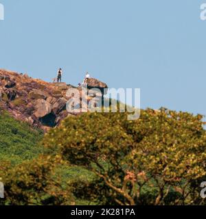 Zwei Menschen mit Hunden unterhalten sich im Pancake Stone auf Ilkley Moor, West Yorkshire, England, Großbritannien Stockfoto