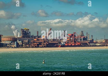 Europa, Frankreich, Dunkerque - 9. Juli 2022: Hafenlandschaft. Kohlekraftwerk am Energy Dock mit roten Kränen und Kraftwerk unter blauer Wolkenlandschaft. Stockfoto