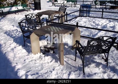 Ein Schachbretttisch aus Beton mit einem schweren Eisensessel Stockfoto