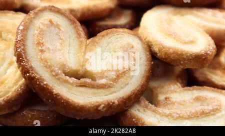 Frische Blätterteigpalmenkekse in Herzform. Klassisches französisches Gebäck. Schweinsohr, Elefantenohrkekse, französische Herzen. Blick von oben Stockfoto