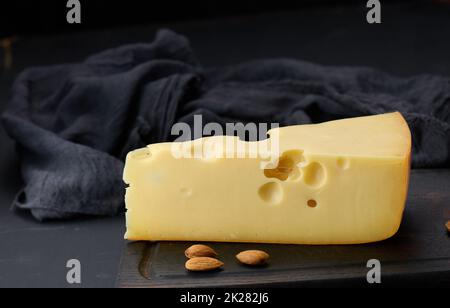 Dreieckiges Stück maasdam-Käse auf einem braunen Holzbrett Stockfoto