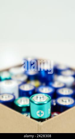 Eine Pappschachtel auf weißem Hintergrund, gefüllt mit gebrauchten AA- und AAA-Alkaline-Batterien, die zum Recycling gesammelt werden. Recycling und ökologische Probleme. Stockfoto