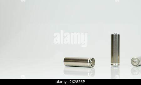 AA-Alkaline-Akkus auf weißem, glänzendem Hintergrund mit Reflexion. Schließen Sie drei leere Batterien mit Platz für Kopien. Stockfoto