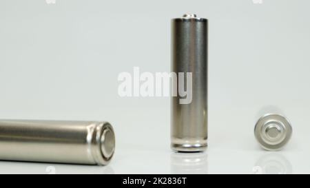 AA-Alkaline-Akkus auf weißem, glänzendem Hintergrund mit Reflexion. Schließen Sie drei leere Batterien mit Platz für Kopien. Stockfoto
