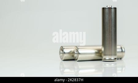 AA-Alkaline-Akkus auf weißem, glänzendem Hintergrund mit Reflexion. Schließen Sie drei leere Batterien mit Platz für Kopien. Stockfoto